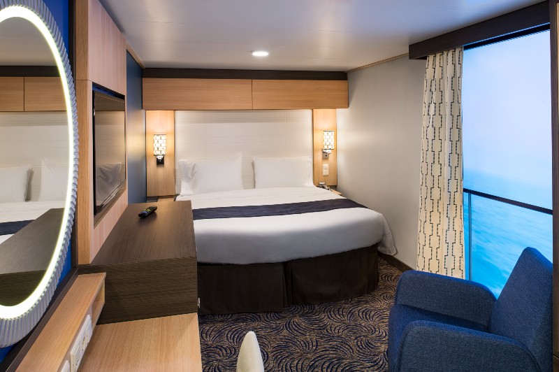 A modern stateroom on Royal Caribbean's Anthem of the Seas with a virtual balcony, featuring a large bed, contemporary decor, and an LED screen displaying real-time ocean views, creating an innovative cruise experience.